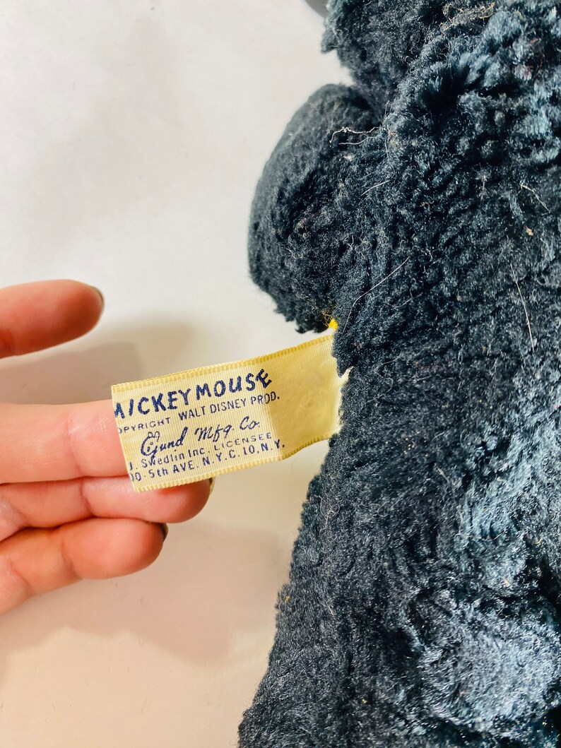 May include: Vintage Mickey Mouse plush toy with a black fur-like fabric. The tag reads "Mickey Mouse Copyright Walt Disney Prod. Gund Mfg. Co. J. Swedlin Inc. Licensee 10-5th Ave. N.Y.C. 10.N.Y."