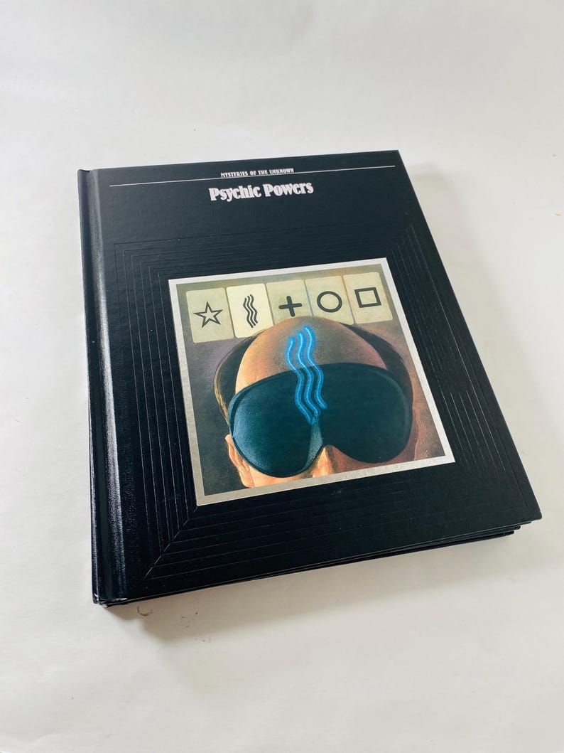 May include: A hardcover book titled "Mysteries of the Unknown: Psychic Powers." The cover is black with the title in white. The image on the cover features a person wearing a sleep mask with blue lines and symbols.