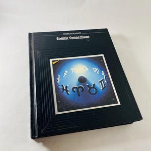 May include: A hardcover book titled "Mysteries of the Unknown: Cosmic Connections." The cover features a dark blue background with a central image of a blue and white celestial design with zodiac symbols.