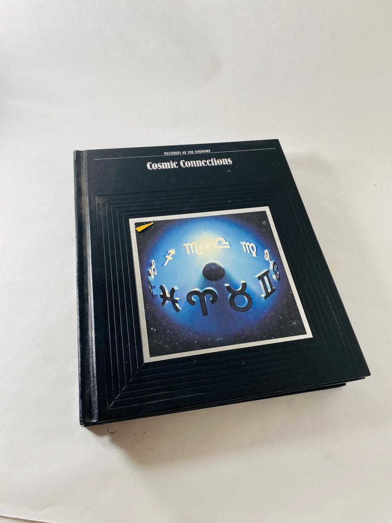 May include: A hardcover book titled "Mysteries of the Unknown: Cosmic Connections." The cover features a dark blue background with a central image of a blue and white celestial design with zodiac symbols.