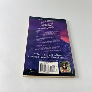 Pu&ograve; includere: Un libro tascabile intitolato Xena: All I Need to Know I Learned From the Warrior Princess. La quarta di copertina presenta uno sfondo viola con testo bianco, una piccola fotografia di una donna, un codice a barre e il logo Universal.