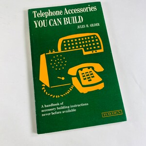 Könnte beinhalten: Ein grünes Buch mit dem Titel "Telephone Accessories You Can Build" von Jules H. Gilder. Der Buchumschlag zeigt eine gelbe Illustration eines Wählscheibentelefons und eines Freisprechtelefons.