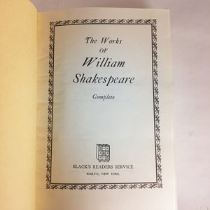 May include: Open book with the title "The Works of William Shakespeare" in a decorative frame. The book is from Black's Readers Service, Roslyn, New York. The pages are off-white with a red bookmark.