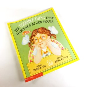 May include: A yellow and green book cover with the title "The Terrible Thing That Happened At Our House". The cover features a cartoon illustration of a young girl with glasses and pigtails, looking sad.
