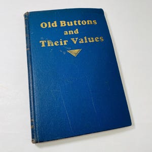 May include: A blue hardcover book with gold lettering titled "Old Buttons and Their Values".