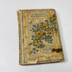 May include: Vintage book titled "Paradise Regained" by Milton. The cover features a floral design with yellow and green flowers on a beige background. The book shows signs of wear and age.