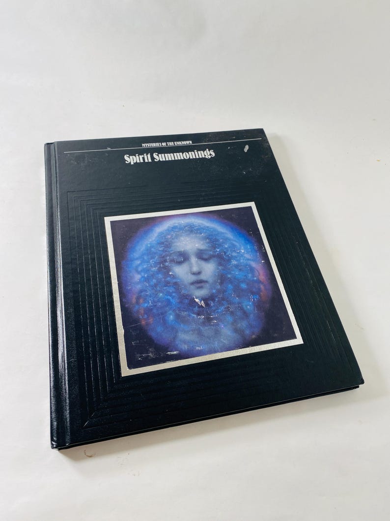May include: A black hardcover book titled "Spirit Summonings" with a blue and white image of a person on the cover. The book is part of the "Mysteries of the Unknown" series.