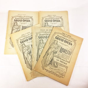 May include: A stack of five vintage Metropolitan Opera House librettos for the operas "La Vestale" and "I Pagliacci". The librettos are printed on yellowed paper with black ink and feature illustrations of women in elaborate costumes.