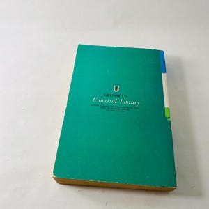 K&ouml;nnte beinhalten: Ein Vintage-Buch aus der Universal Library von Grosset. Das Buch hat einen t&uuml;rkisfarbenen Einband mit dem Serientitel und Logo in Wei&szlig;. Der Buchr&uuml;cken ist blau, wei&szlig; und gr&uuml;n. Die Seitenr&auml;nder sind vergilbt.