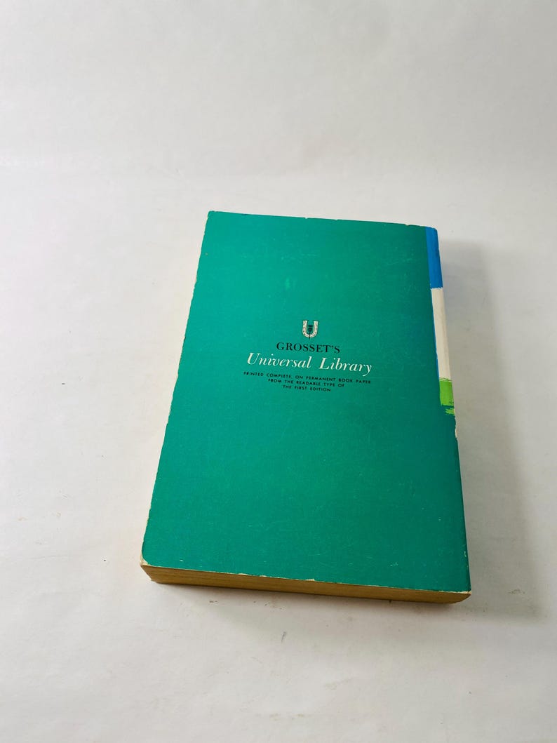 K&ouml;nnte beinhalten: Ein Vintage-Buch aus der Universal Library von Grosset. Das Buch hat einen t&uuml;rkisfarbenen Einband mit dem Serientitel und Logo in Wei&szlig;. Der Buchr&uuml;cken ist blau, wei&szlig; und gr&uuml;n. Die Seitenr&auml;nder sind vergilbt.
