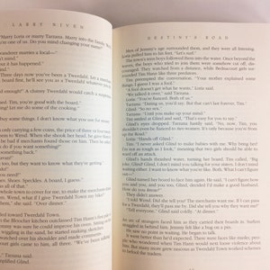 May include: A close-up of an open book with a white background. The book is open to a page with the title "Destiny's Road" and text about a young man named Tim who is trying to fit in with a new community. The text includes dialogue between Tim and other characters.