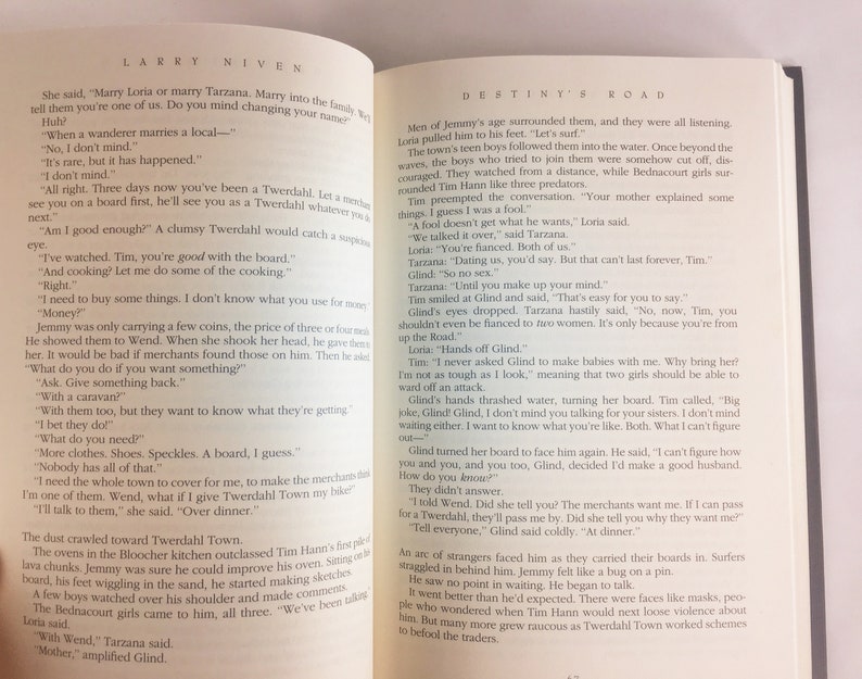May include: A close-up of an open book with a white background. The book is open to a page with the title "Destiny's Road" and text about a young man named Tim who is trying to fit in with a new community. The text includes dialogue between Tim and other characters.