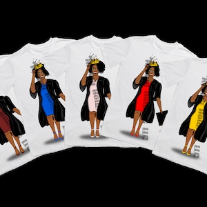 May include: Five white t-shirts with a graphic of a Black woman wearing a graduation cap and gown, a crown, and a different colored dress on each shirt. The dresses are red, pink, blue, yellow, and maroon.