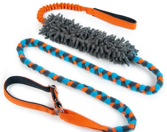 May include: Three dog toys are displayed against a white background. The toys include an orange bungee-style leash with a black handle, a gray plush toy, and a blue and orange braided leash with a black handle and metal hardware.