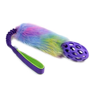 Puede incluir: Un juguete para perros colorido con una cola de felpa de color arcoíris, unida a un asa morada con interior verde. También se incluye una bola morada hueca. Diseñado para el juego interactivo.