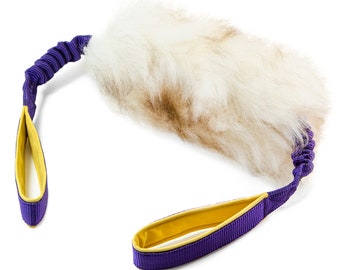 May include: A white and brown furry dog toy with a purple and yellow rope handle.