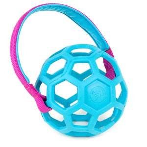 Puede incluir: Un juguete para perros en forma de bola azul turquesa, con un asa rosa y turquesa. La bola tiene un patrón geométrico y un logotipo en la parte delantera. El asa está hecha de un material tejido rosa y turquesa.