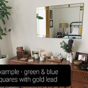 May include: A rectangular mirror with gold trim and green and blue squares. The mirror is above a wooden dresser with various decorative items, including candles, a tray of perfumes, and framed photos. The text on the image says: example - green & blue squares with gold lead.