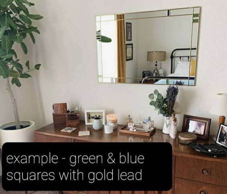 May include: A rectangular mirror with gold trim and green and blue squares. The mirror is above a wooden dresser with various decorative items, including candles, a tray of perfumes, and framed photos. The text on the image says: example - green & blue squares with gold lead.