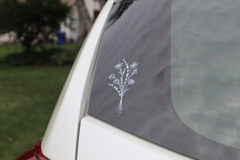 May include: White car window with a white outline sticker of a bouquet of flowers.