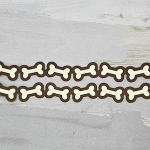 May include: Two rows of brown paper bone shapes with a white center, arranged in a repeating pattern on a gray background.