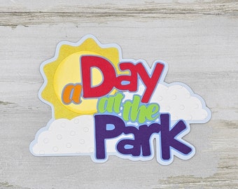 May include: A colorful paper craft with a sun, clouds, and the text "a Day at the Park" in rainbow colors.