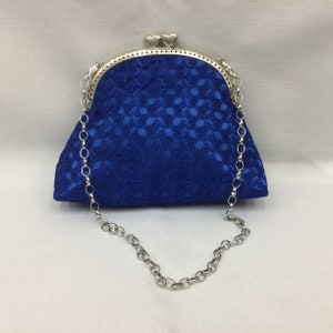 May include: A royal blue lace clutch with a silver chain strap and a heart-shaped clasp.