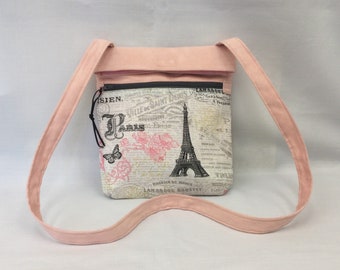 Puede incluir: Un bolso de bandolera rosa con cierre de cremallera y un estampado en blanco y negro con la Torre Eiffel y la palabra "París".
