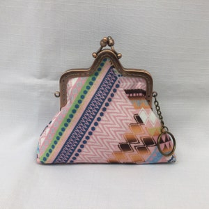 Può includere: Un porta monete con motivo rosa e blu con una chiusura in ottone e una catena con un portachiavi.