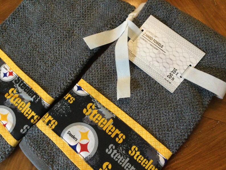 May include: Two gray hand towels with yellow trim and a black and white Steelers logo. The towels are 16 x 26 inches.