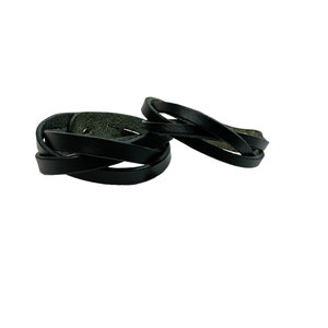 Peut inclure: Deux bracelets en cuir noir, l'un enroulé autour de l'autre, créant un effet tressé.