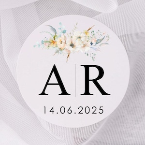 Könnte beinhalten: Ein weißer Kreis mit einem floralen Design und den Buchstaben "AR" in Schwarz mit dem Datum "14.06.2025" darunter.