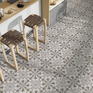 May include: Three wooden bar stools with brown woven seats, arranged in a row, facing a counter. The stools are set on a tiled floor with a geometric pattern of brown and grey floral shapes.