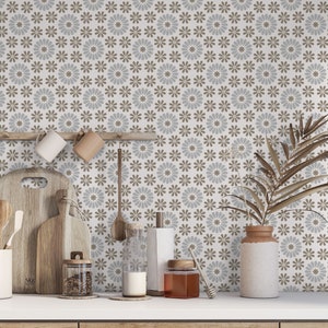 May include: A kitchen countertop with a patterned tile backsplash featuring brown and blue floral designs. The countertop has a variety of kitchen items, including wooden chopping boards, mugs, utensils, and jars.