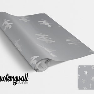 Könnte beinhalten: Eine Rolle graue Tapete mit einem weißen abstrakten Muster. Die Tapete ist aufgerollt und das Etikett "quote my wall vinyl & prints" ist am unteren Rand des Bildes sichtbar.