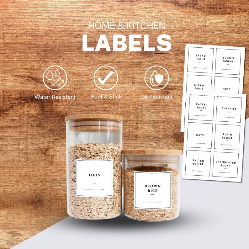May include: Two glass jars with cork lids and white labels. The labels have black text that reads "Oats" and "Brown Rice". The jars are sitting on a wooden surface. There are several sheets of white labels with black text on a wooden surface. The labels include "Bread Flour", "Brown Sugar", "Mixed Fruit", "Nuts", "Caster Sugar", "Cherries", "Oats", "Plain Flour", "Salted Butter", and "Granulated Sugar".