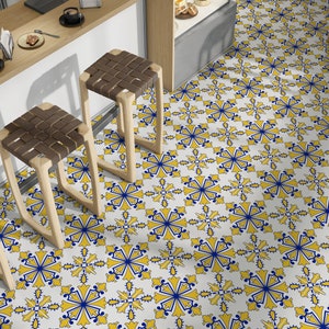 May include: A white tiled floor with a repeating pattern of blue and yellow geometric shapes. Three wooden bar stools with woven brown seats are in the foreground.