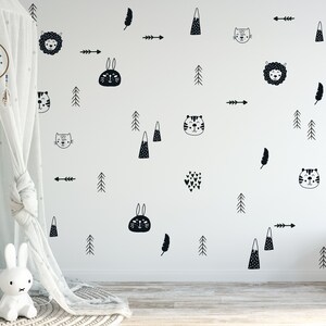May include: Black and white wall decals featuring various animal and nature designs, including a lion, a rabbit, a cat, a tiger, a feather, a mountain, a tree, and an arrow. The decals are on a white wall.