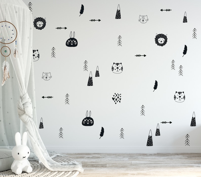 May include: Black and white wall decals featuring various animal and nature designs, including a lion, a rabbit, a cat, a tiger, a feather, a mountain, a tree, and an arrow. The decals are on a white wall.