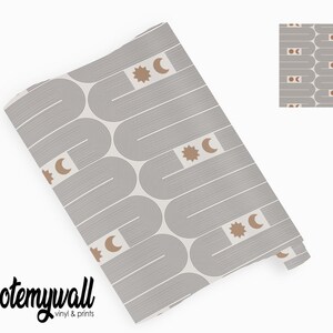 Puede incluir: Rollo de papel pintado con un patr&oacute;n repetitivo de arcos grises, l&iacute;neas y formas geom&eacute;tricas. El dise&ntilde;o incluye motivos de sol y luna creciente marrones. La marca "quotemywall" est&aacute; impresa en negro en la parte inferior.