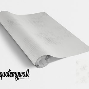 Puede incluir: Un rollo de papel tapiz de vinilo blanco texturizado con un sutil patrón gris. El papel tapiz está enrollado y el extremo del rollo es visible. La imagen también muestra un primer plano del patrón del papel tapiz.