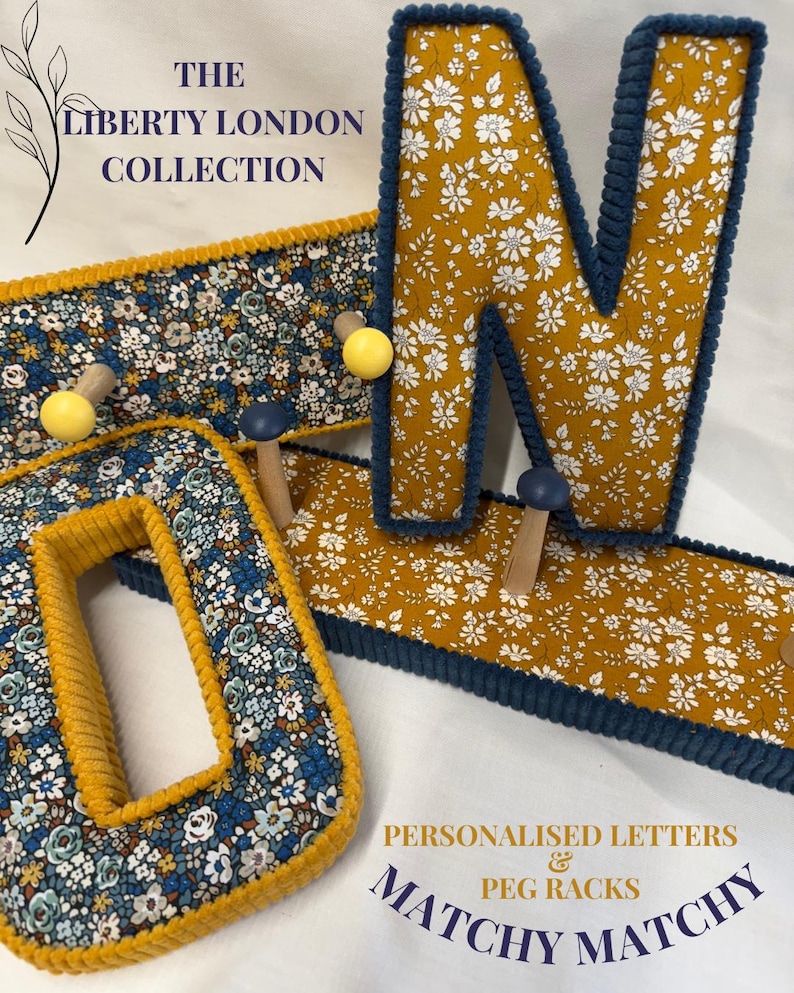 Puede incluir: Una letra O y una letra N decorativas, y un perchero, todos cubiertos de tela floral con ribetes de pana en color amarillo mostaza y azul marino. El texto dice THE LIBERTY LONDON COLLECTION y PERSONALISED LETTERS & PEG RACKS MATCHY MATCHY.