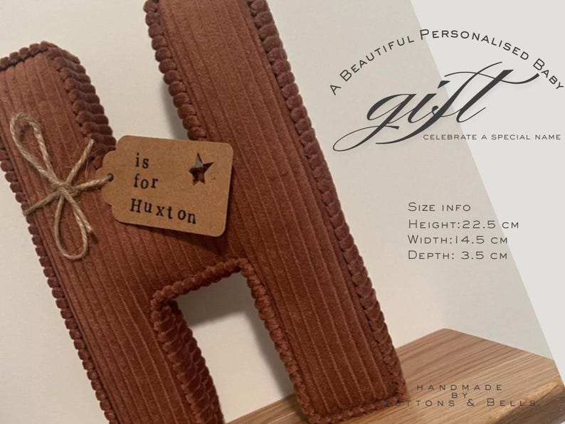 May include: A brown corduroy letter "H" with a tag that reads "is for Huxton". The letter is 8.9 inches tall, 5.7 inches wide, and 1.4 inches deep. The image also includes the text "A BEAUTIFUL PERSONALISED BABY GIFT CELEBRATE A SPECIAL NAME".