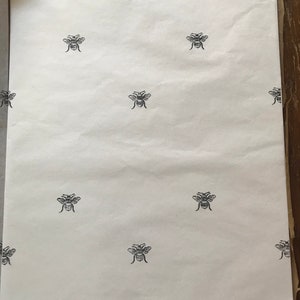 May include: White tissue paper with a repeating pattern of black bee silhouettes.