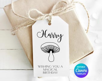 Può includere: Un'etichetta regalo rettangolare bianca con un foro in alto, che presenta il nome Harry in corsivo nero, un disegno al tratto nero di un fungo e il testo WISHING YOU A MAGICAL BIRTHDAY. L'etichetta è legata con dello spago a un pacchetto.