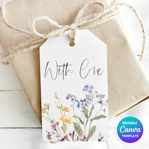 Puede incluir: Una etiqueta de regalo blanca con las palabras "With Love" en escritura cursiva, adornada con flores de acuarela en tonos azules, amarillos y morados. La etiqueta está atada a un regalo envuelto con hilo. La etiqueta también tiene un logotipo de plantilla de Canva.