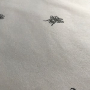 May include: White wrapping paper with a repeating pattern of black bees.