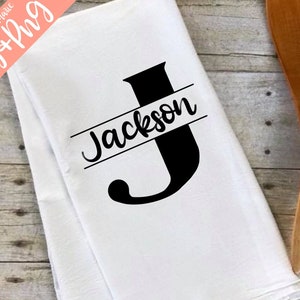 May include: White kitchen towel with a black letter J and the name Jackson printed across the top of the letter.