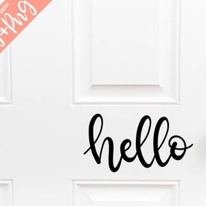 May include: A white door with a black cursive "hello" decal on the lower half of the door. The door has a silver door knob and a silver deadbolt lock.