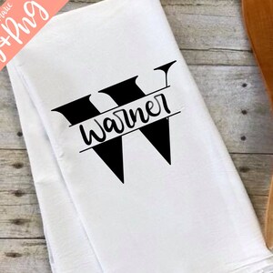 May include: A white kitchen towel with a black letter W and the name "Warner" written across the center of the letter.